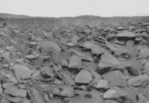 A black and white image showing a rocky plain. 