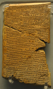 An image showing a clay tablet, cracked and chipped, covered in cuneiform carving.