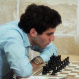 Photograph of Garry Kasparov looking at black chess pieces on a chessboard