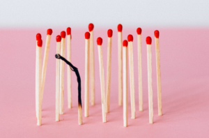 Matchsticks on pink surface with one burnt, visually representing burnout