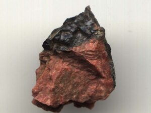 A rock sample from the Ytterby mine. It's arrowhead-like in shape, mostly red, and black at the tip. The black portion is the famous gadolinite.