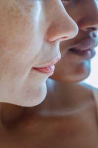 Close up of the side profiles of two women from the nose to the chin. 