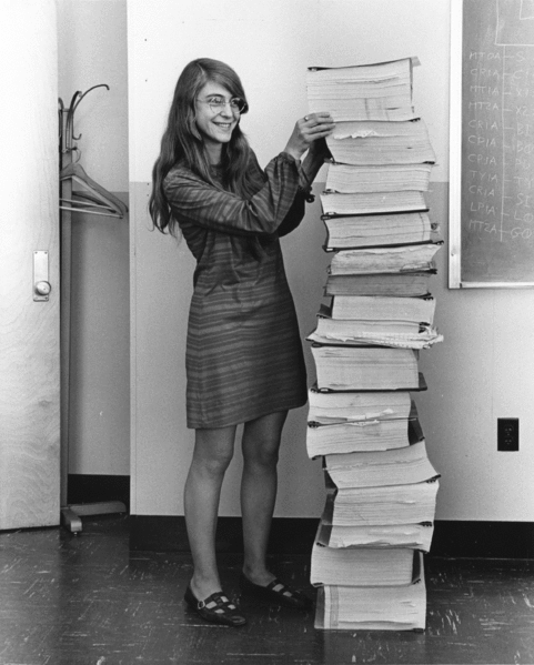 Photograph of Margaret Hamilton next to a tall pile of books